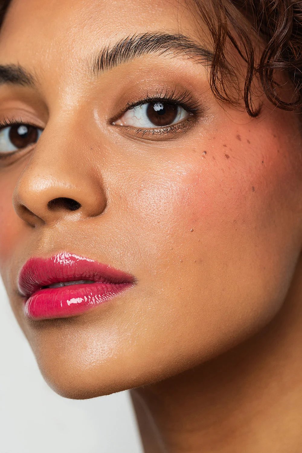 Model wears glossy pink lip stain with glowing cheek color.