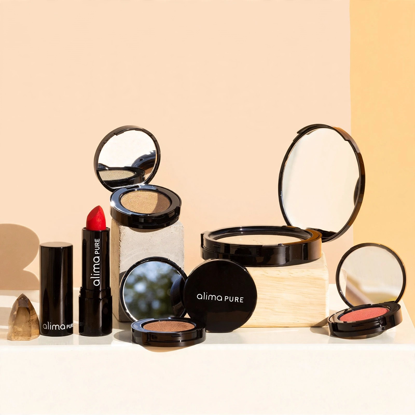Open Alima Pure compacts, blush and lipstick displayed on blocks.