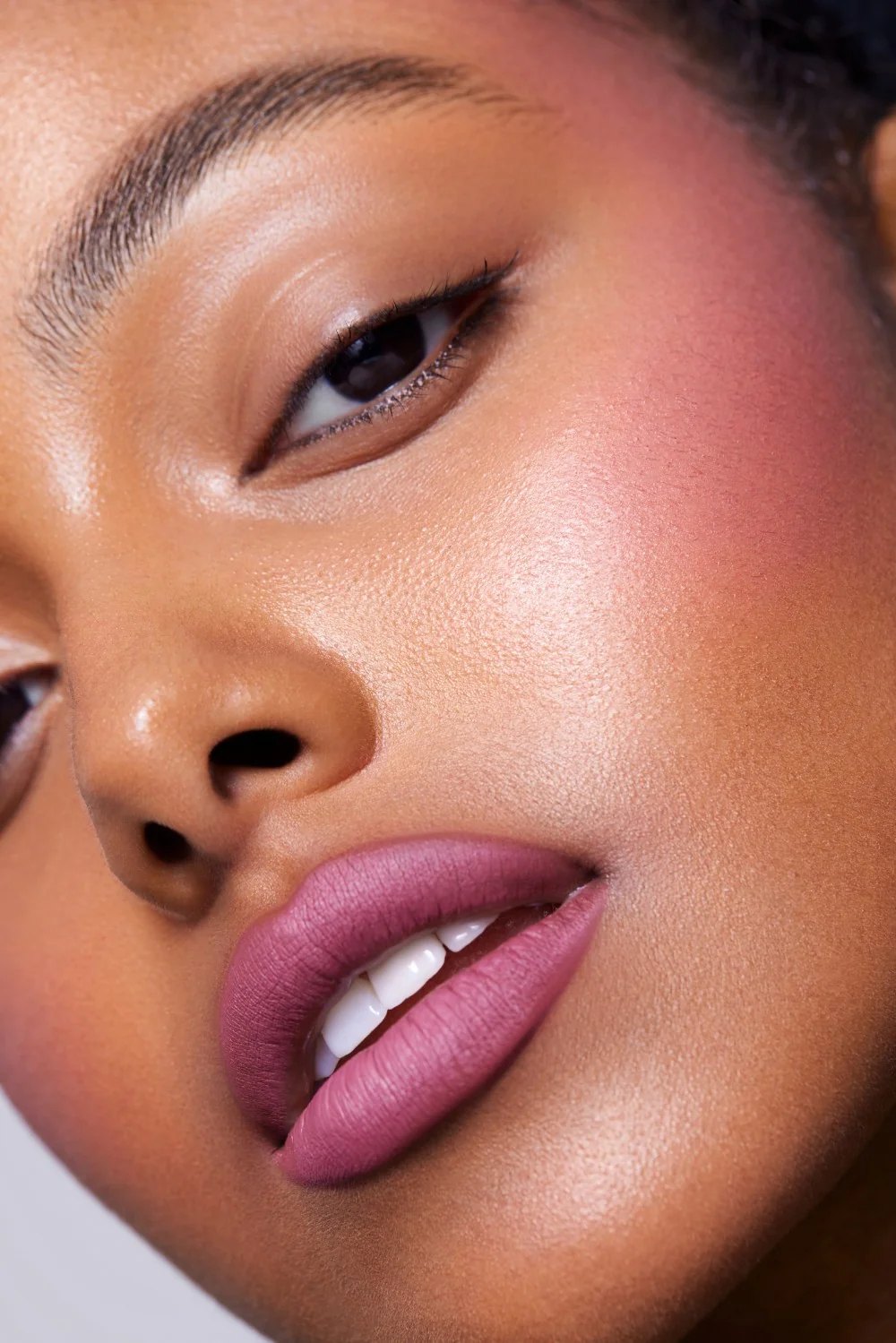 Closeup of a model wearing matte pink makeup on lips and cheeks.