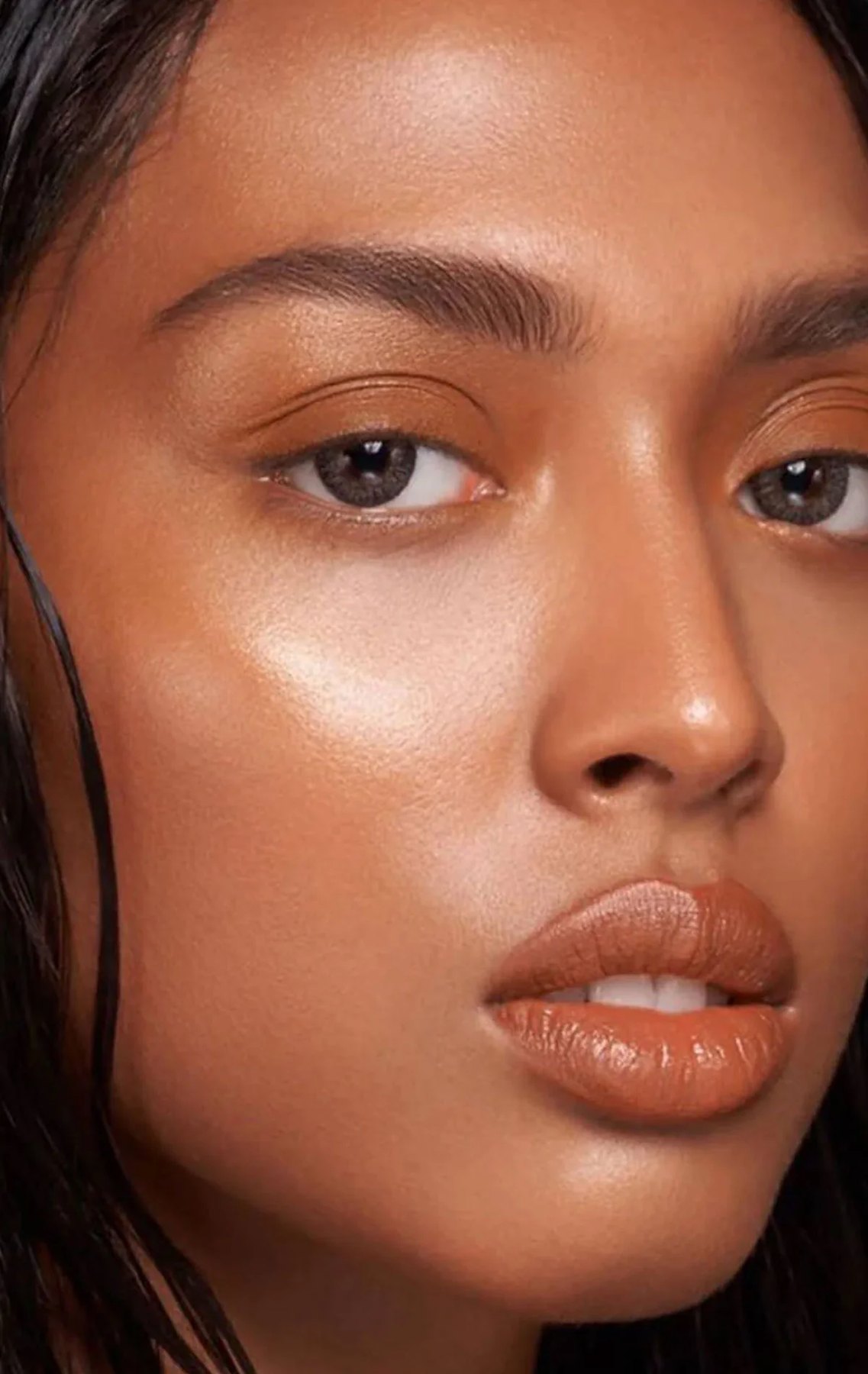 Closeup of a model with glowing skin and glossy nude lips.
