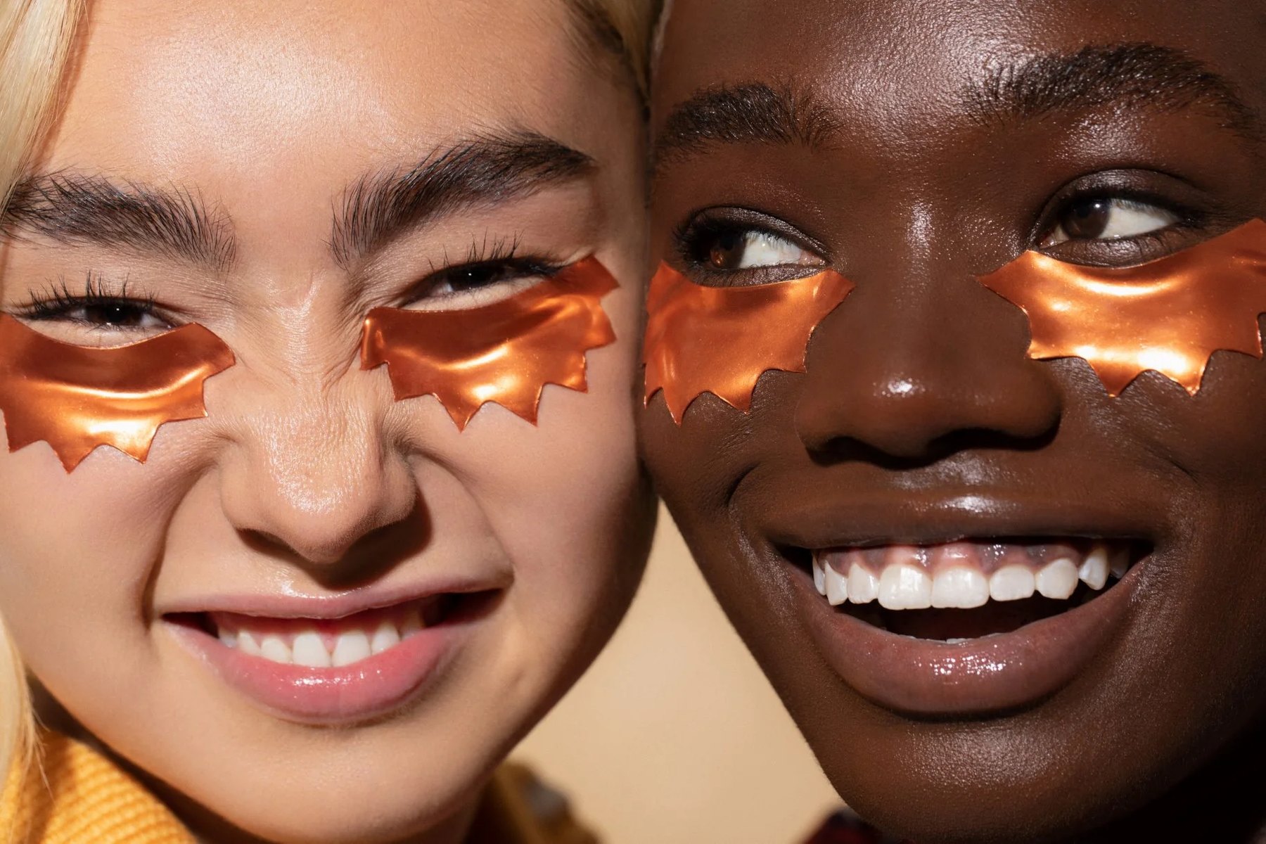 Two women smiling while wearing copper under eye patches.