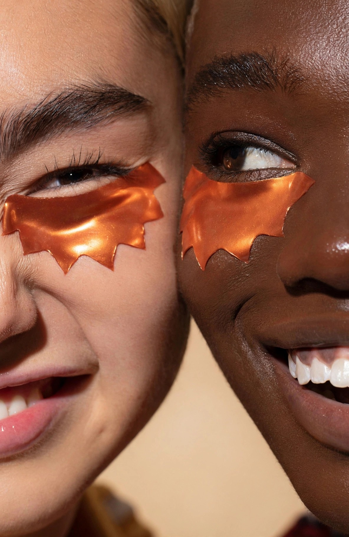 Close crop of two women wearing metallic orange eye patches.