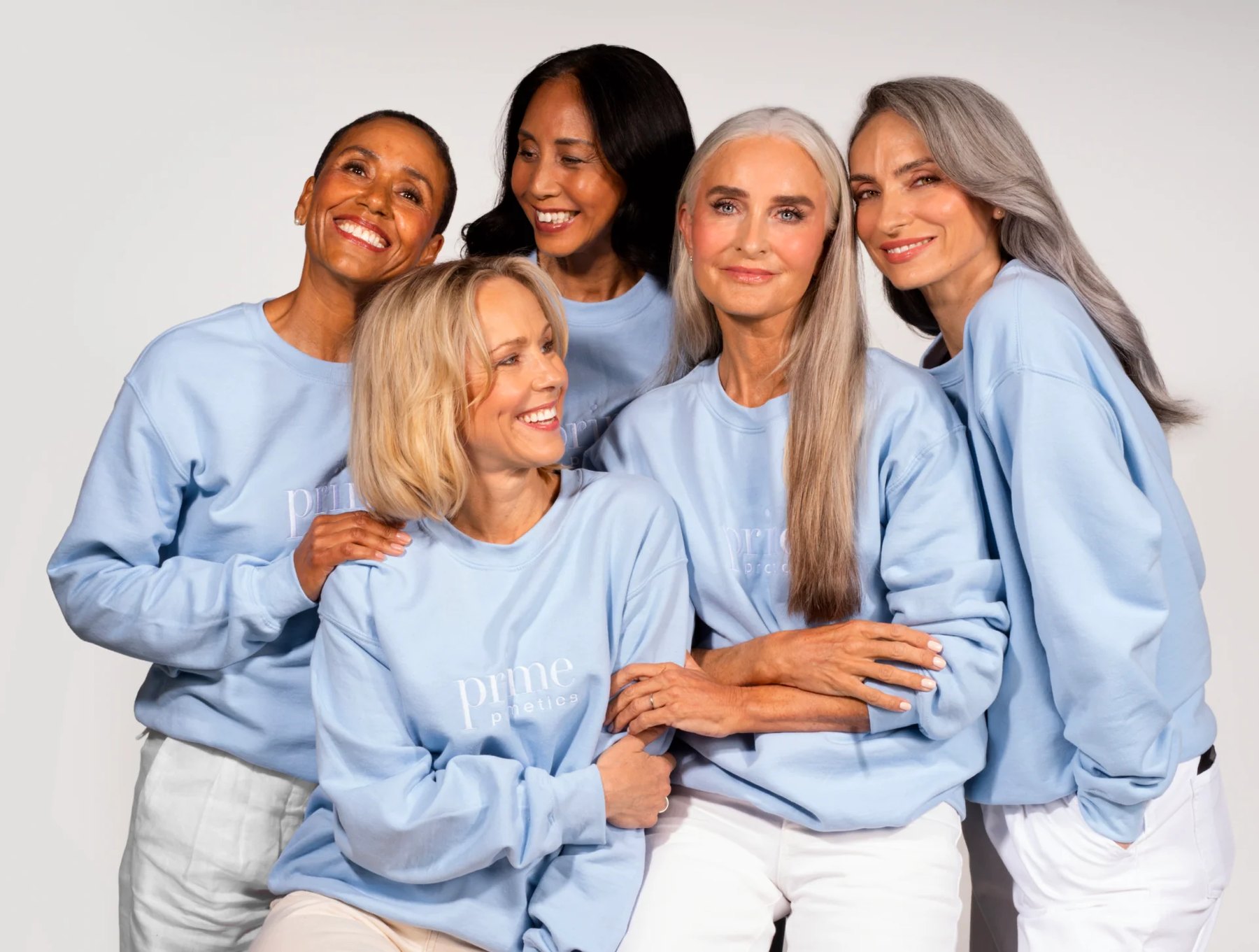 Five women in matching blue sweatshirts posing together and smiling.