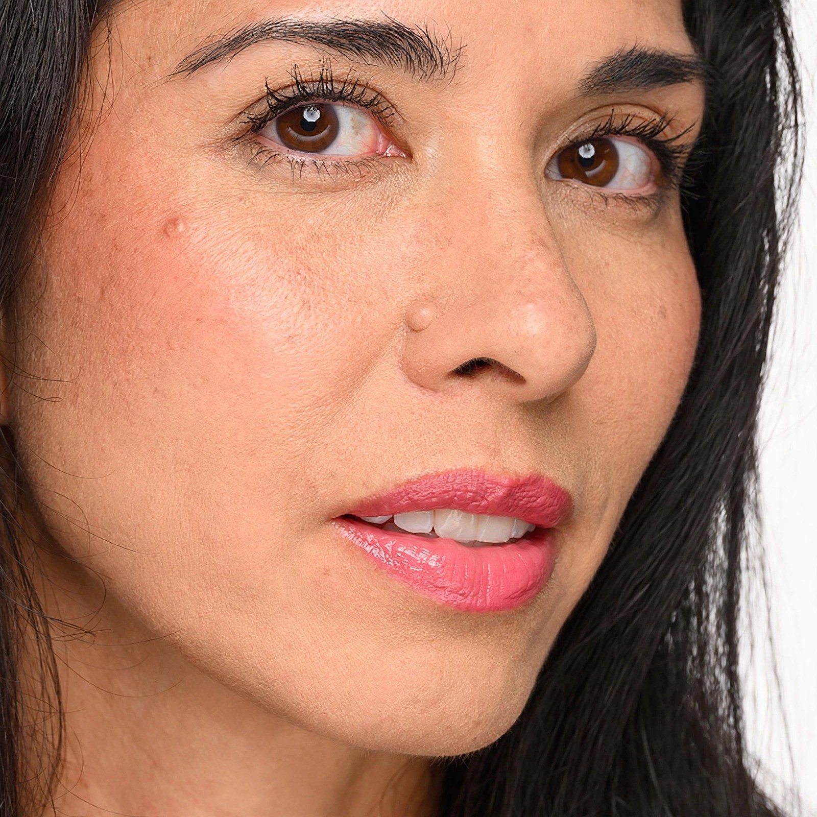 Closeup of a woman wearing mascara and pink lip color.