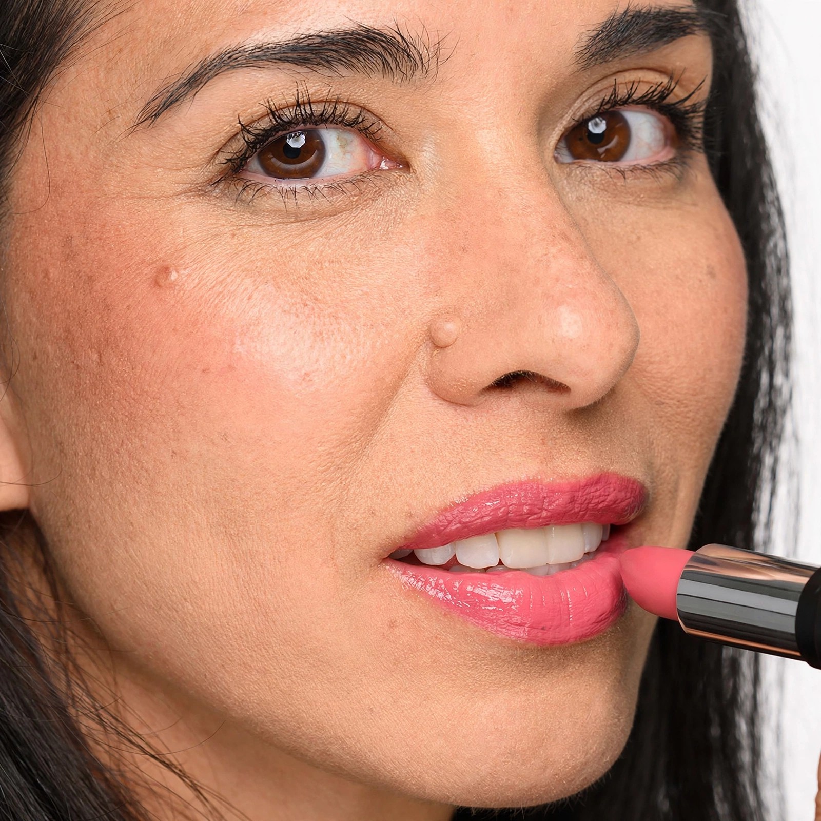 Woman applying pink lipstick in a closeup beauty portrait.