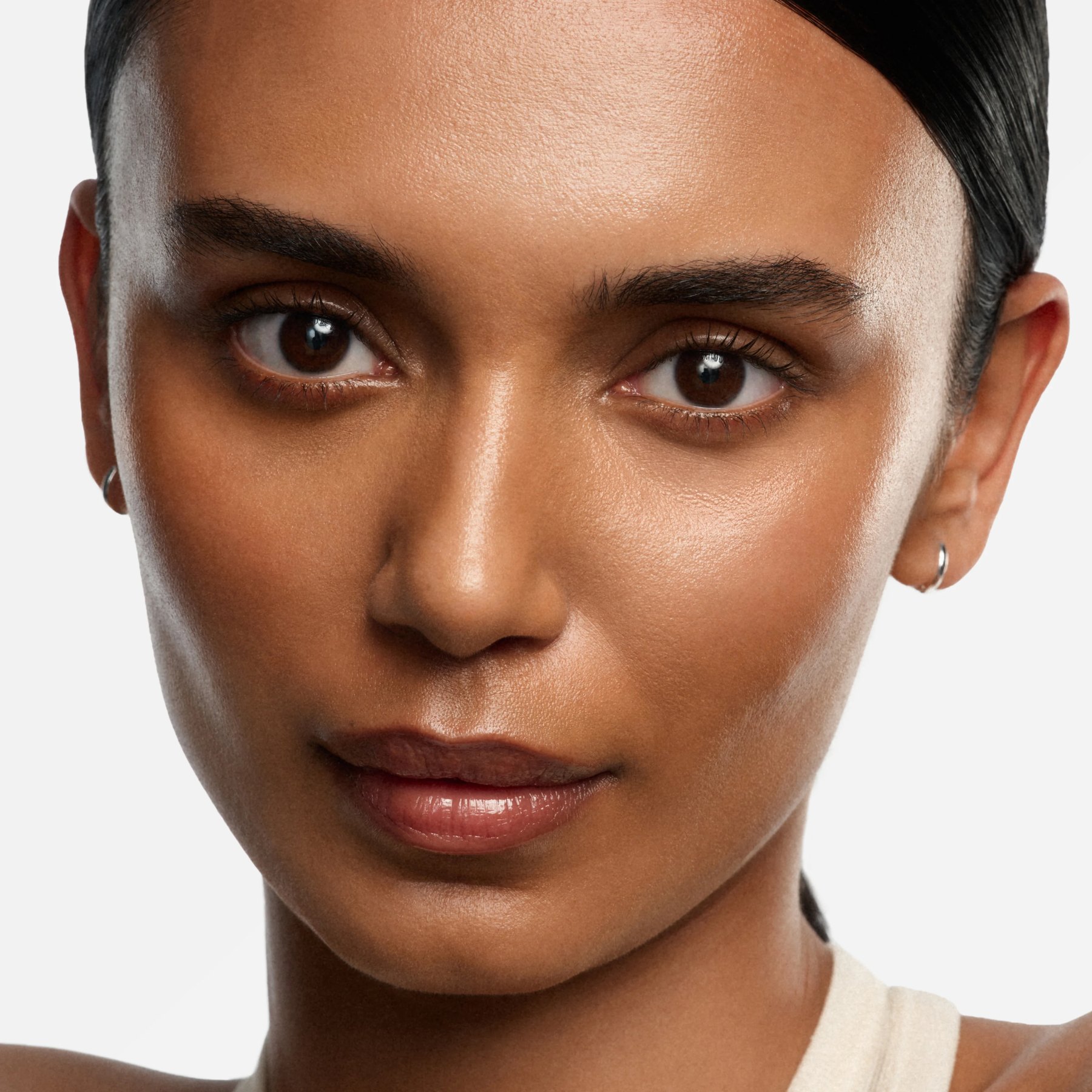 Model with glowing skin showing Saie Glowy Super Gel finish.