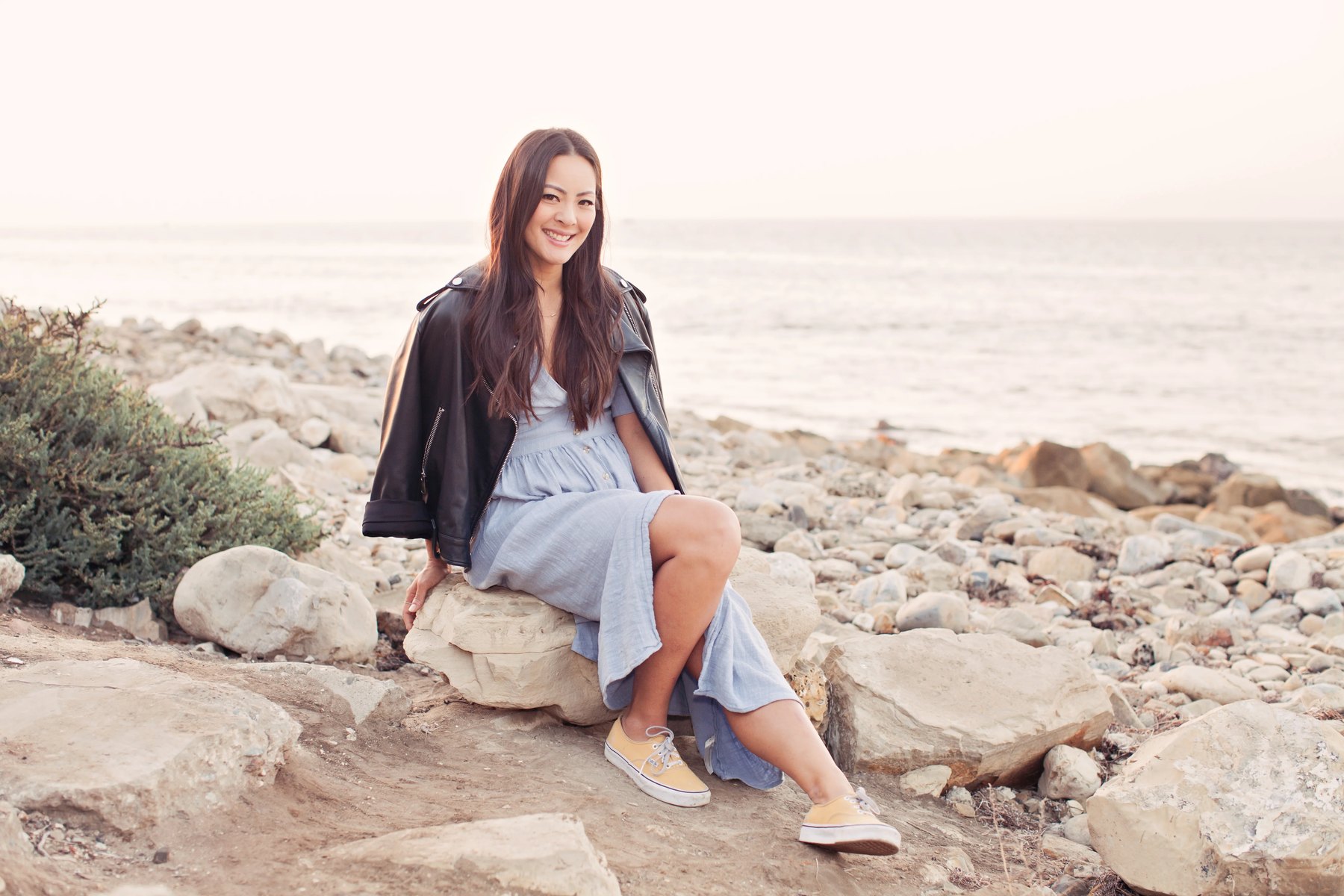 Amy Liu sitting on rocks at the beach in daylight.